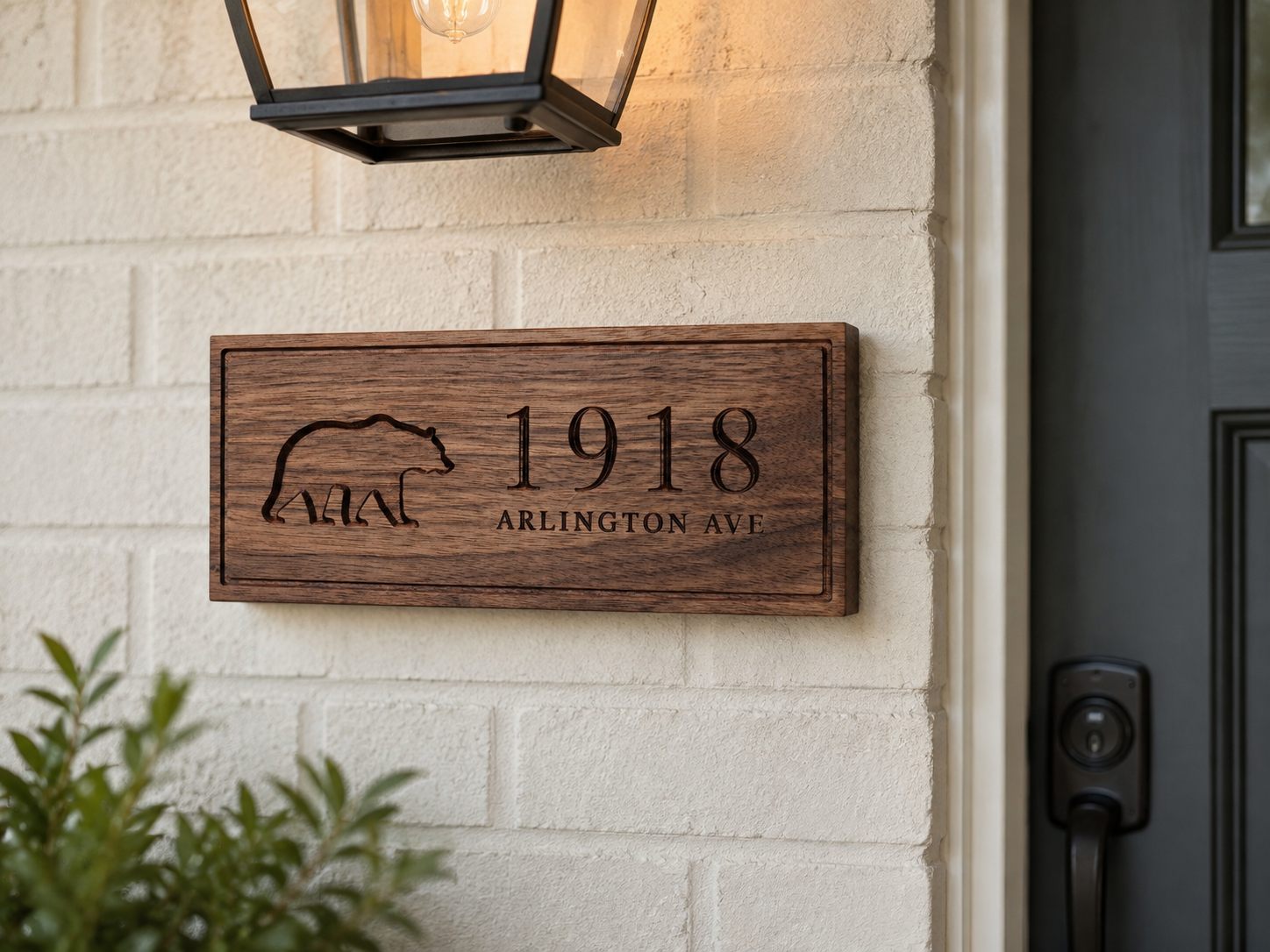 Carved walnut house number plaque with bear motif reading 1918 Arlington Ave, mounted beside a front door